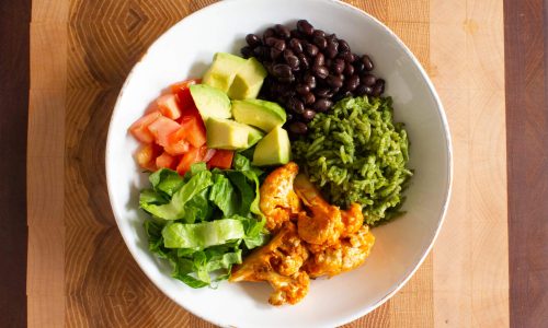 Colorful bowl with black beans, avocado, lettuce, tomato, guacamole, and chicken. Colorful bowl with black beans, avocado, lettuce, tomato, guacamole, and chicken.